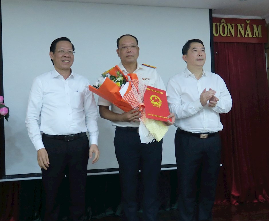 Đồng chí Phan Văn Mãi, Chủ tịch UBND Thành phố và đồng chí Cao Anh Tuấn, Thứ trưởng Bộ Tài chính trao quyết định và tặng hoa cho đồng chí Vũ Xuân Bách.